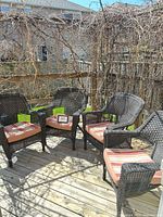 Four synthetic wicker patio chairs with striped cushions on deck