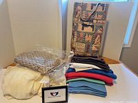 overview of all items: folded fabrics, pillow-sham in plastic, frame, tapestry bag