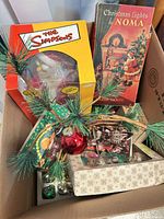 Overall contents in box showing Simpsons ornament, NOMA lights box, ornaments, garland