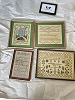 Group shot of four framed cross stitch samplers on packing paper