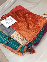 Stack of folded scarves and shawls showing textures, colors and tassels