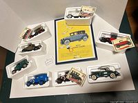 Overhead view of all eight cars in styrofoam trays surrounding framed Willys Sainte Claire print