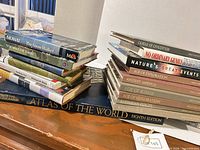 Two stacks of assorted hardcover and paperback books including Atlas of the World and Time-Life series