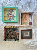 All four framed art pieces arranged on surface, showing front views