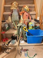 Full lot on stairs showing scarecrows, tools, blue tote, feeder and accessories