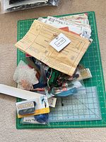 Lot overview on green cutting mat with patterns, zippers, trims, Velcro pack and ruler