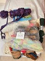 Bundle overview with various yarn skeins, needles, plastic canvas and booklet