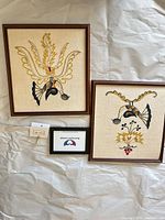 Both framed embroideries side by side on surface