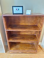 Front view of brown solid wood bookcase with three shelves
