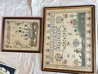 Both framed samplers side by side on linen background