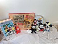 All eight items arranged: boxed cut-outs, puzzle box, tin tray, plush figures, red toy, electric lamp cord visible