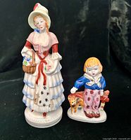Front view of both porcelain figurines: colonial woman and boy with cat