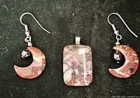 Earrings and pendant laid out on black fabric