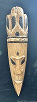 Front view of entire wooden tribal mask showing carved facial features and painted details