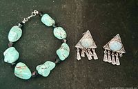 Bracelet and earrings side by side on black background