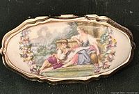 Front view of oval porcelain scarf clip with Fragonard courting couple image