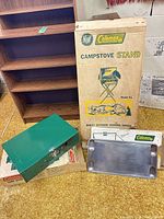 Group shot of camp stove stand box, green stove and aluminum griddle