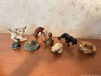 Group shot of eight animal figurines on wooden surface