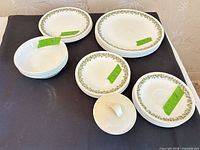 Stacked dinner plates, luncheon plates and saucers, cereal bowls, sugar bowl with lid showing green daisy border