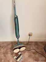Full view of General Electric floor polisher standing upright with cord and installed pads