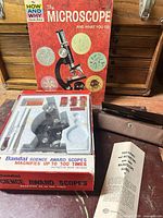 Overall lot with microscope kit box open, book, scalpel case, and pamphlet visible