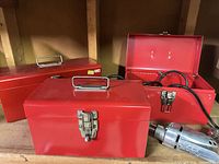 Three red metal toolboxes and Millers Falls drill
