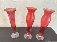 Three ruby red glass vases on clear bases