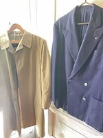 Tan overcoat and purple blazer hanging side by side