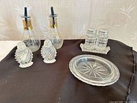 Group shot of all glass items: cruets, shell shakers, waffle shakers, tray, butter dish base