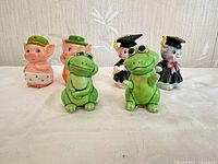 Group shot showing all six ceramic shakers: pigs, frogs, cats