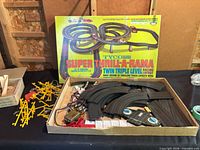 Open box showing track sections, controllers, wiring, guardrails and trestles beneath original box lid
