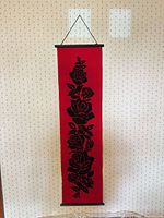 Full view of red banner with black rose pattern hanging on wall