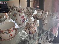 Group of Schumann Dresden Flowers teapot, cream pitcher, sugar bowl, cups and saucers in display cabinet