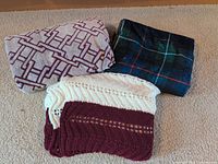 All three blankets folded: geometric fleece, plaid fleece, striped Afghan