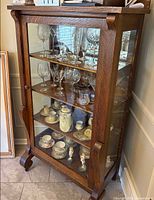 Front view showing glass door, four shelves, tiger oak grain, scrolled feet