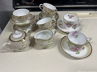 Prussia tea set components displayed on countertop: six cups, six saucers, sugar bowl with lid, creamer