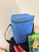 Blue Amway backpack cooler front view with flashlights and grill pan box partially visible