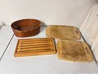 Overall lot: two wood cutting boards, slotted bread board with tray, wicker basket