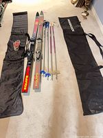 Full lot showing Elan skis, two pairs poles, two Rossignol ski bags