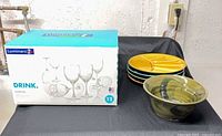 Boxed Luminarc goblet set beside stack of segmented plates and pottery bowl