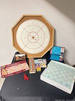 Full lot view showing crokinole board, Scrabble box, Battleship boards, cribbage board, playing cards and glass chess board package