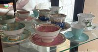 All five teacup and saucer sets displayed on glass shelf