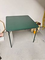 Full view of green folding card table standing on floor