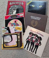 Six LPs spread out showing front covers: Godspell, Cats, Joseph and the Amazing Technicolour Dreamcoat, Jesus Christ Superstar, Monty Python's Flying Circus, Three Amigos