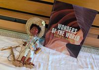 Marionette puppet lying beside hardcover Wonders of the World book