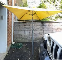 Full view of yellow patio umbrella set up beside vehicle