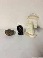 Group shot of all three stone items: thunderegg, black stone face, onyx horse head bookend