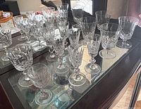 Group of twelve cut-crystal goblets on display shelf