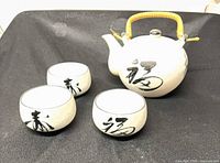 group shot of teapot and three teacups showing calligraphy