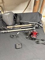 Lot overview showing camera, tripod, charger, cable, bag